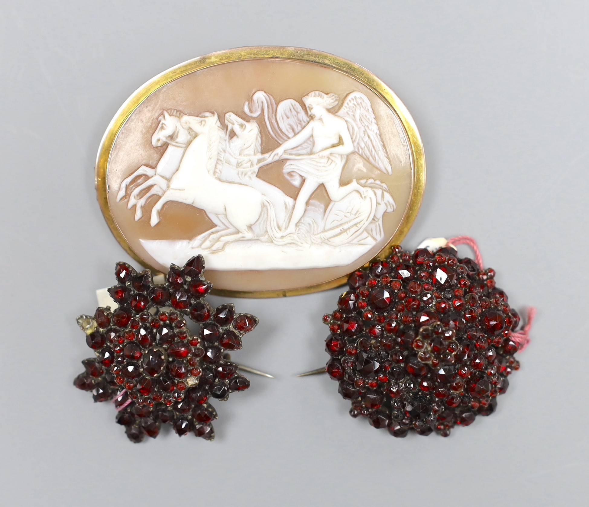 Two Victorian garnet set brooches, largest 3.5cm and a gold mounted cameo brooch, 5.5cm